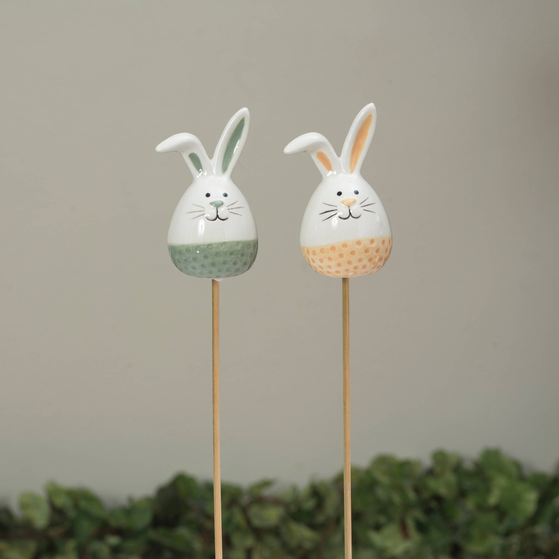Two decorative bunny figures on sticks with a plain background