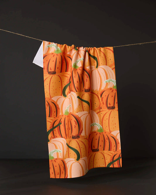 Geometry brand kitchen tea towel with pumpkins pattern hanging on a line against a black background