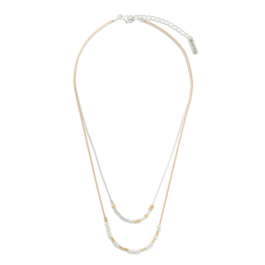 A double-strand necklace featuring one chain in polished gold and one in white gold or platinum, accented with small beads and a central cluster of clear stones, shown on a plain white background stating You're Beautiful in Morse Code.