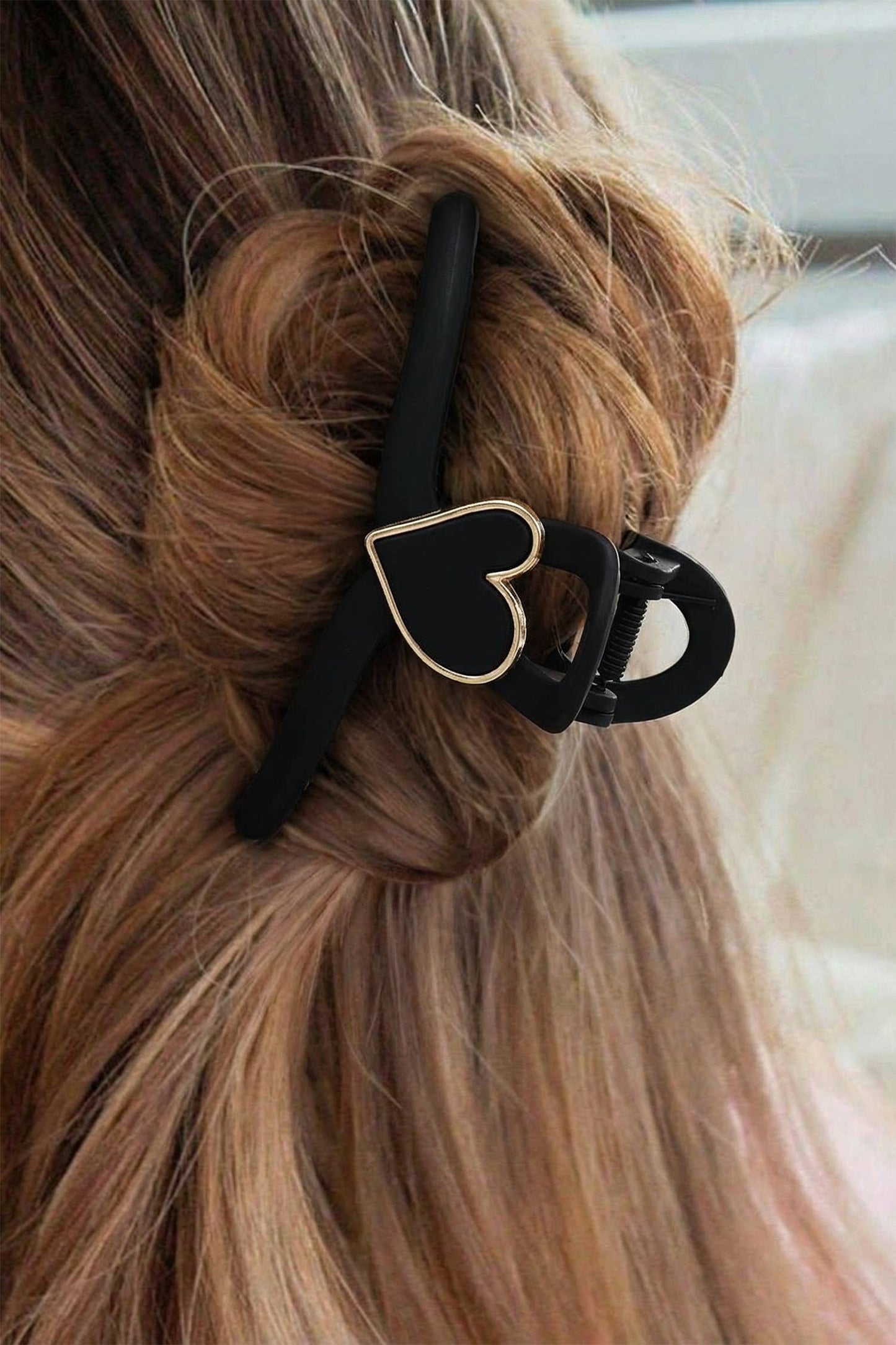 Blonde hair with a black hair clip featuring a heart design.