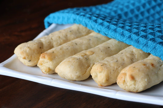 Breadsticks on a white plate with a blue towel underneath