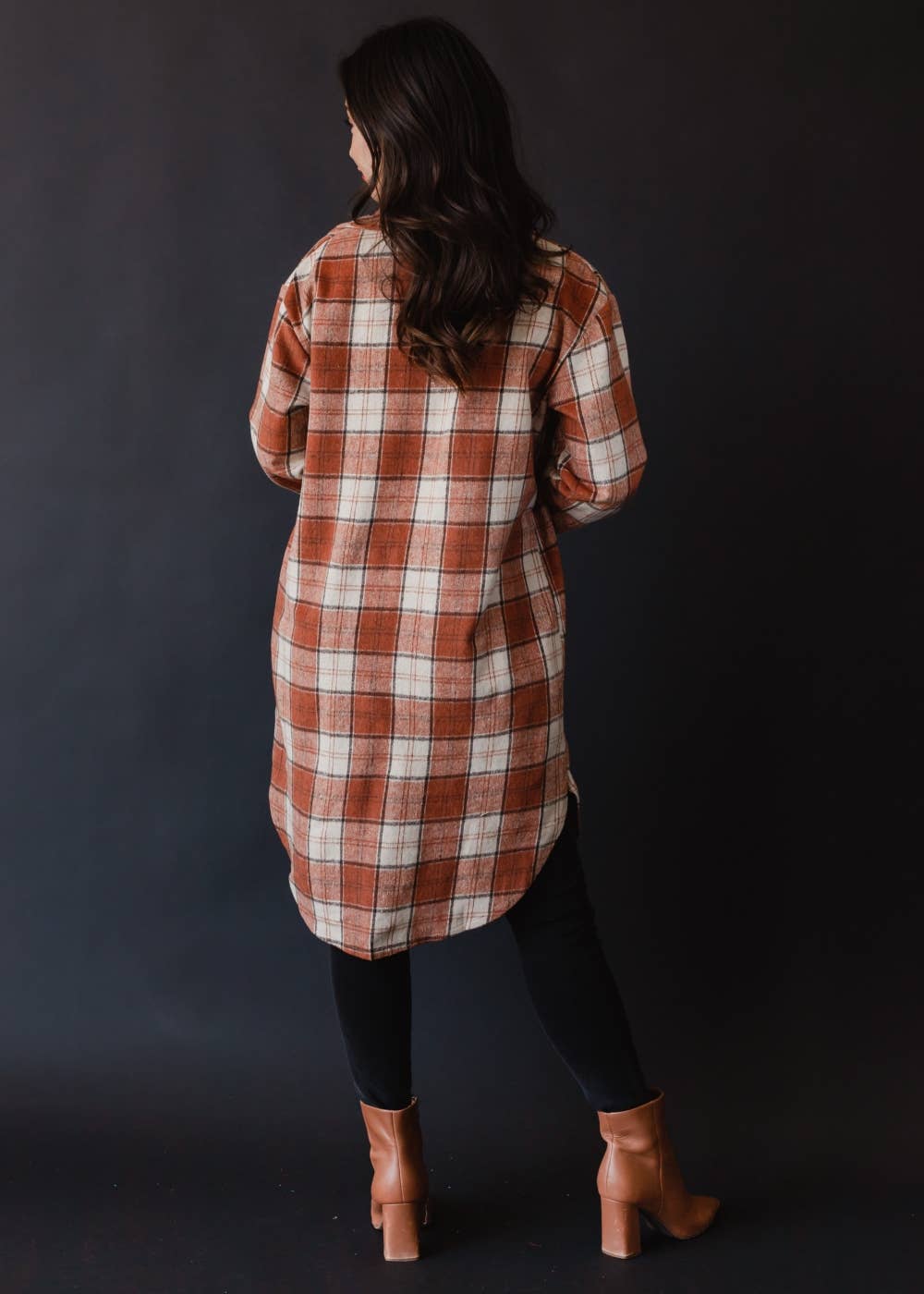 Woman wearing a plaid shirt dress against a dark background