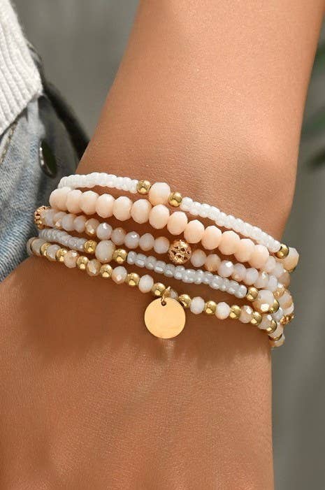 Stack of beaded bracelets on a wrist with a neutral background