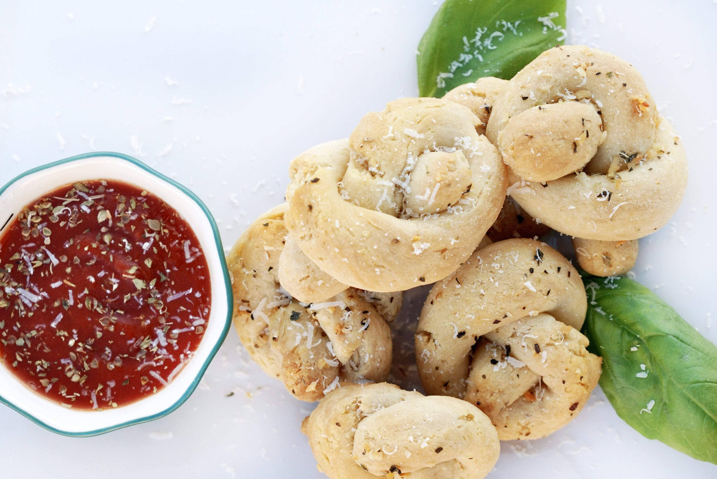 Bread knots with a side of red sauce on a white background