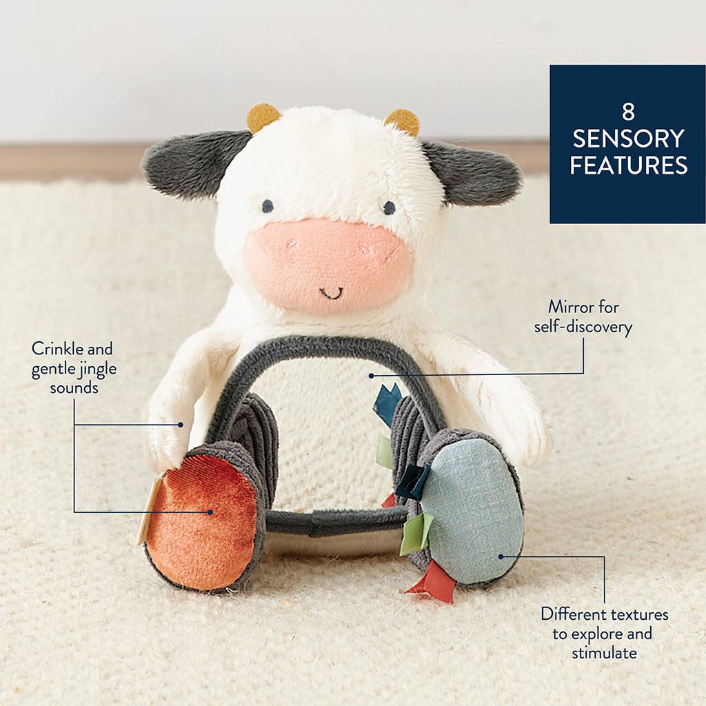 Stuffed cow toy with sensory features labeled on a light background