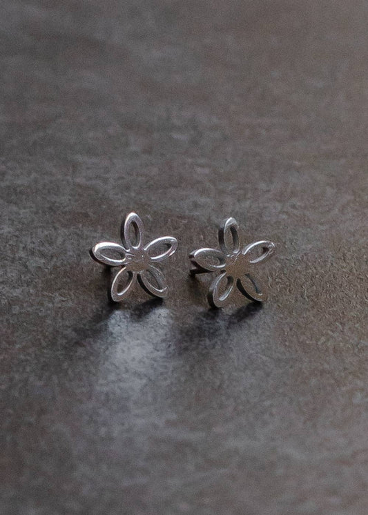 Silver flower-shaped earrings on a dark gray surface