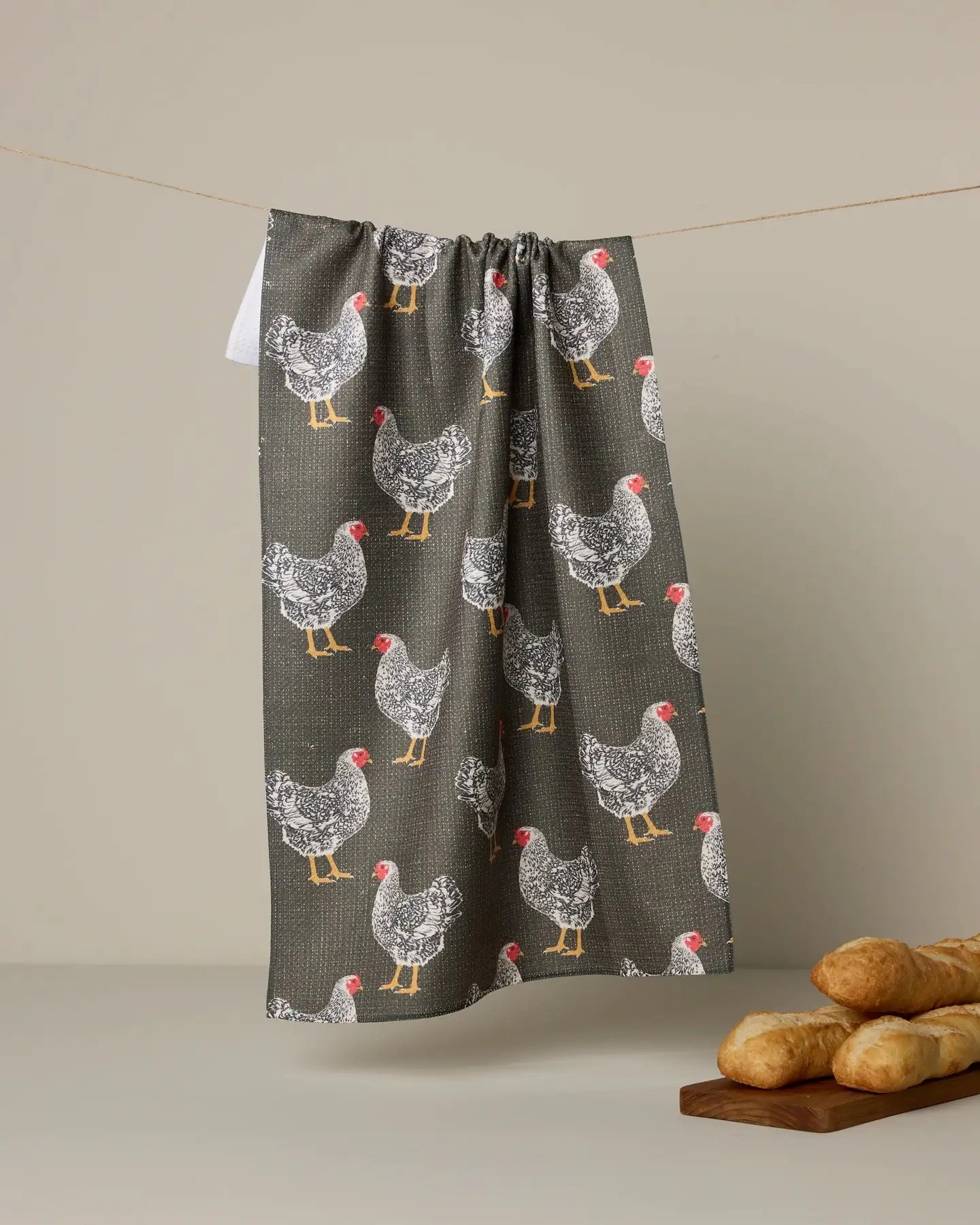 Geometry Tea Towel with chicken pattern hanging on a line against a beige background