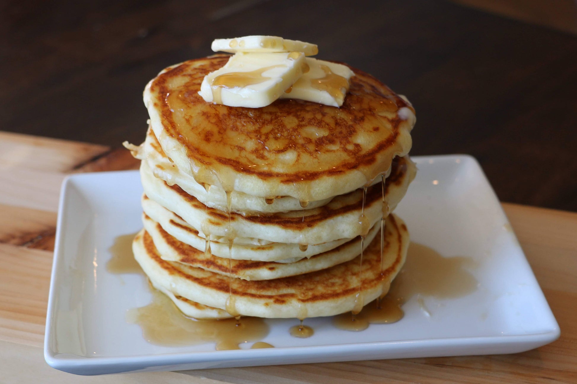 Stack of pancakes with butter and syrup on a white plate