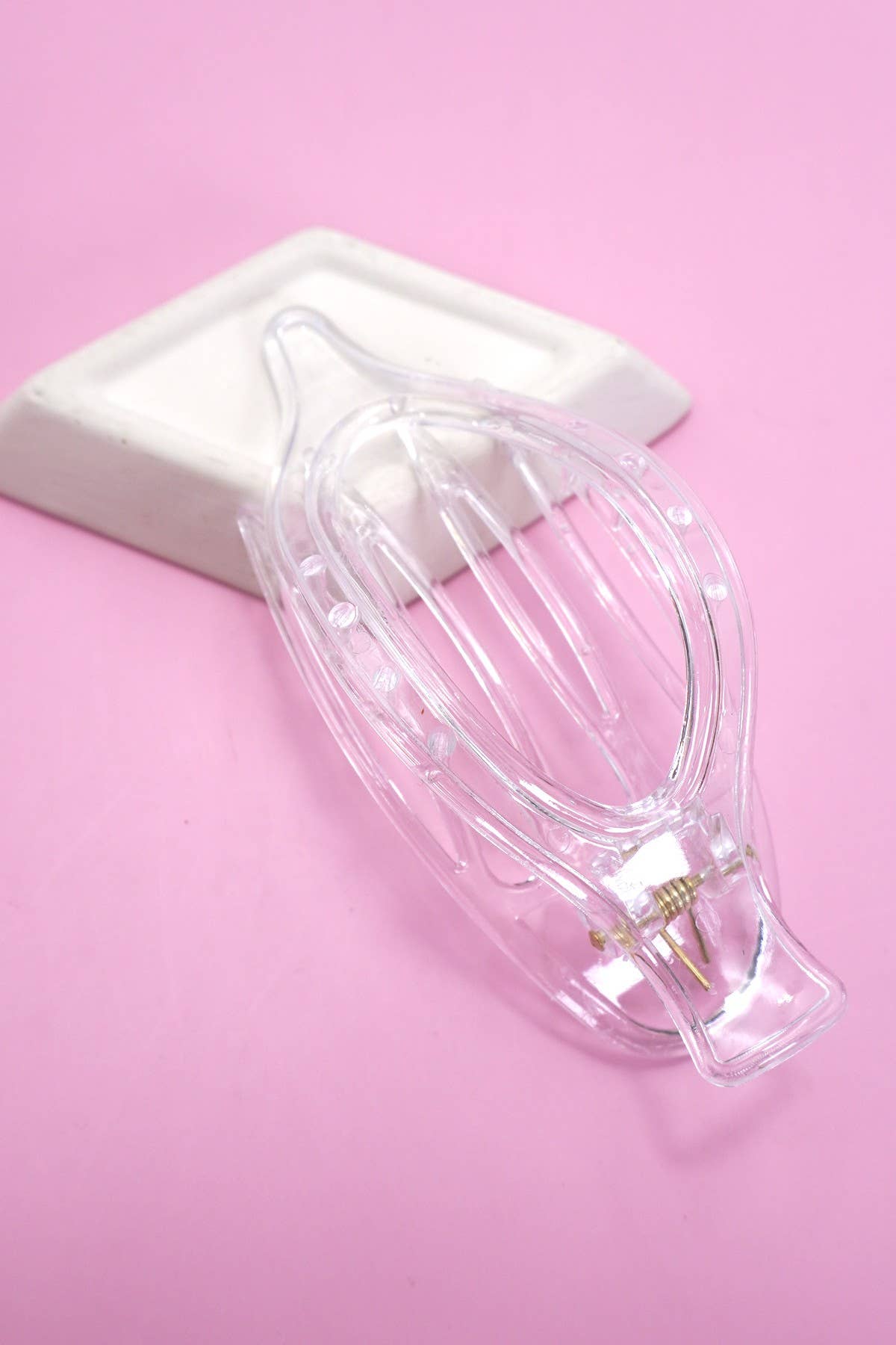 Clear plastic hair clip on a pink background