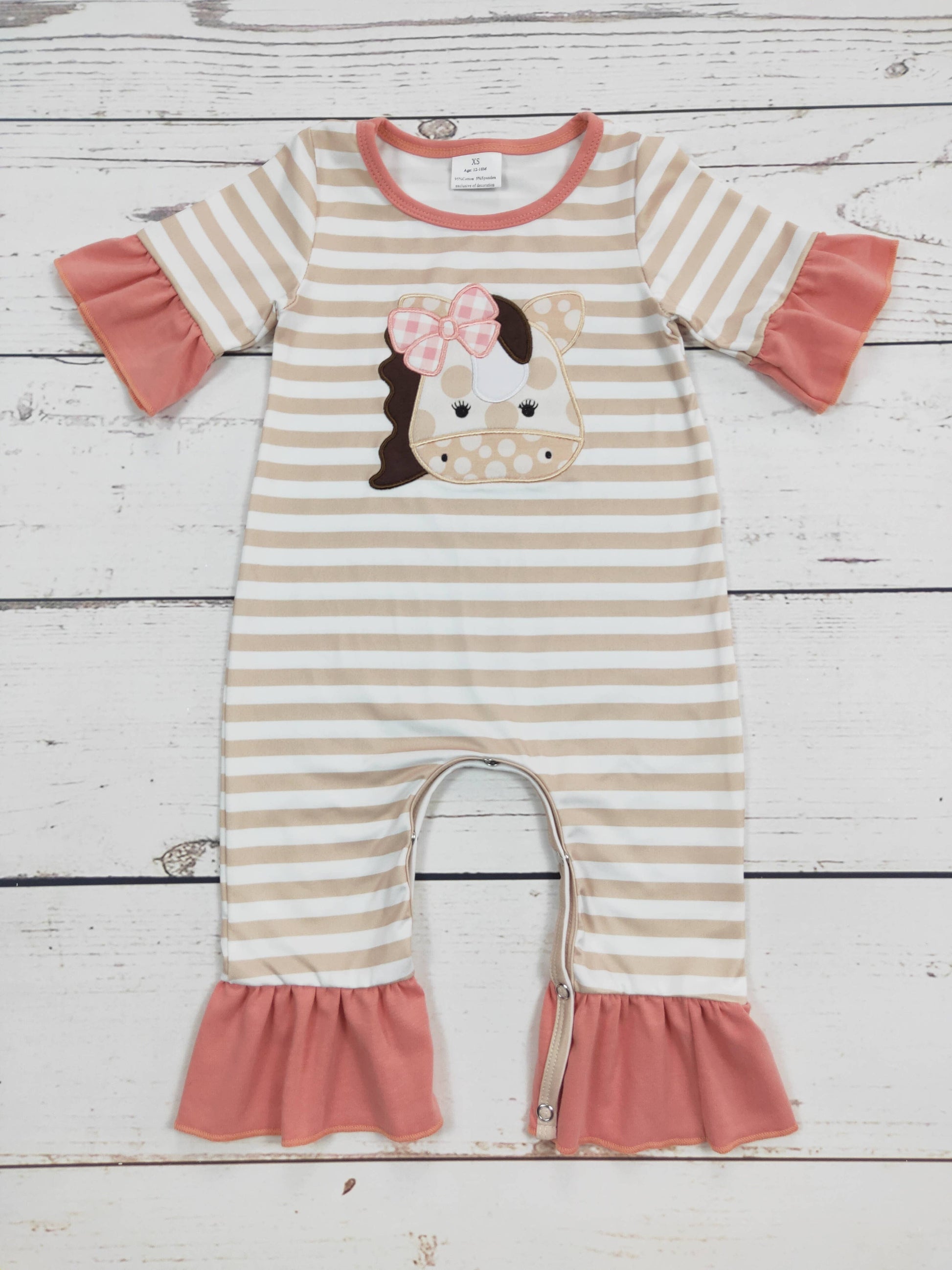 Striped baby romper with a horse design on a wooden surface