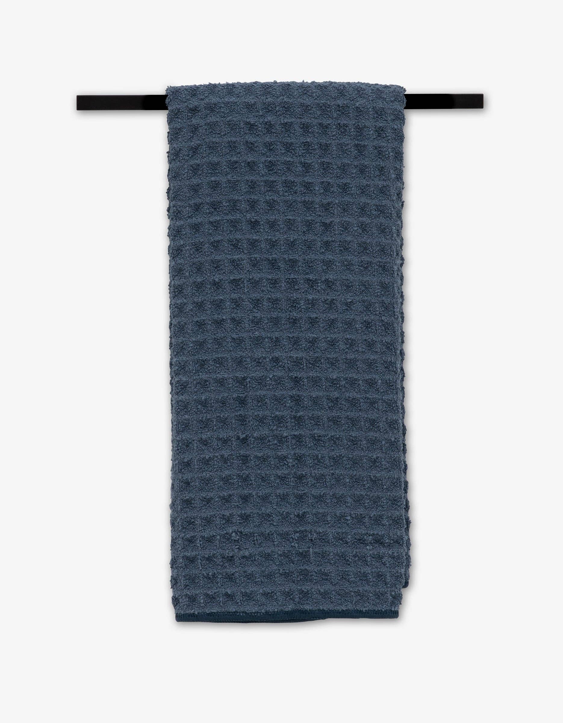 Blue textured towel hanging on a black rod against a white background