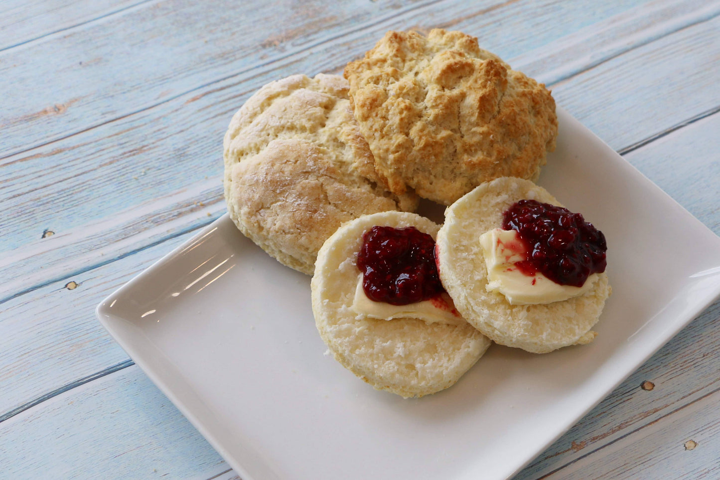 Butter biscuits with jam on a white plate on a wooden surface