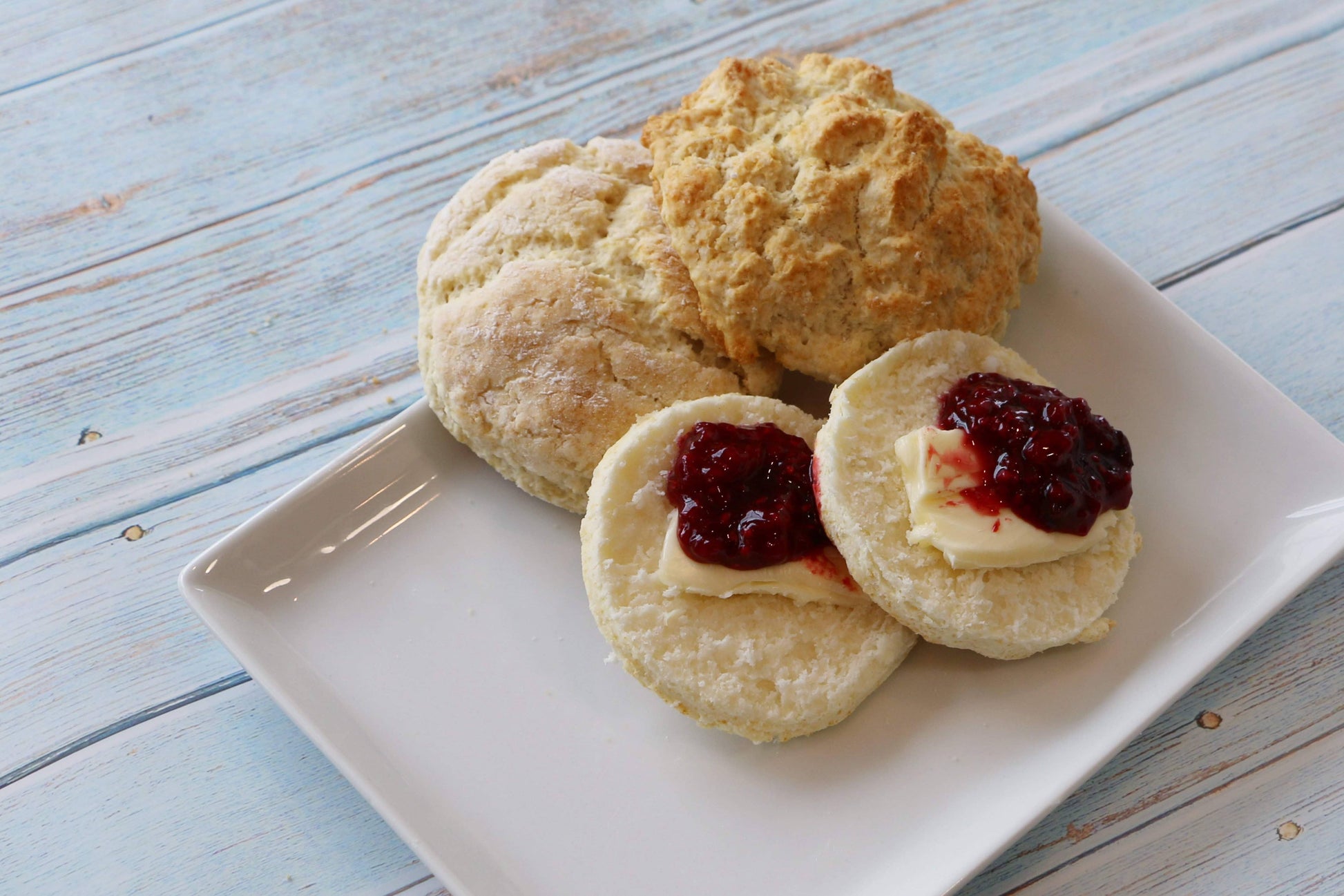 Butter biscuits with jam on a white plate on a wooden surface