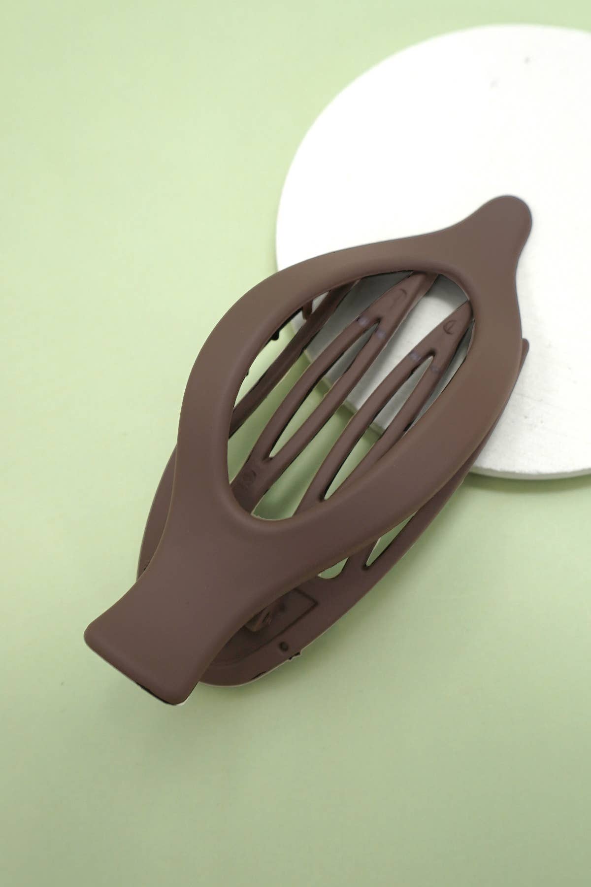 Brown hair clip on a light green background