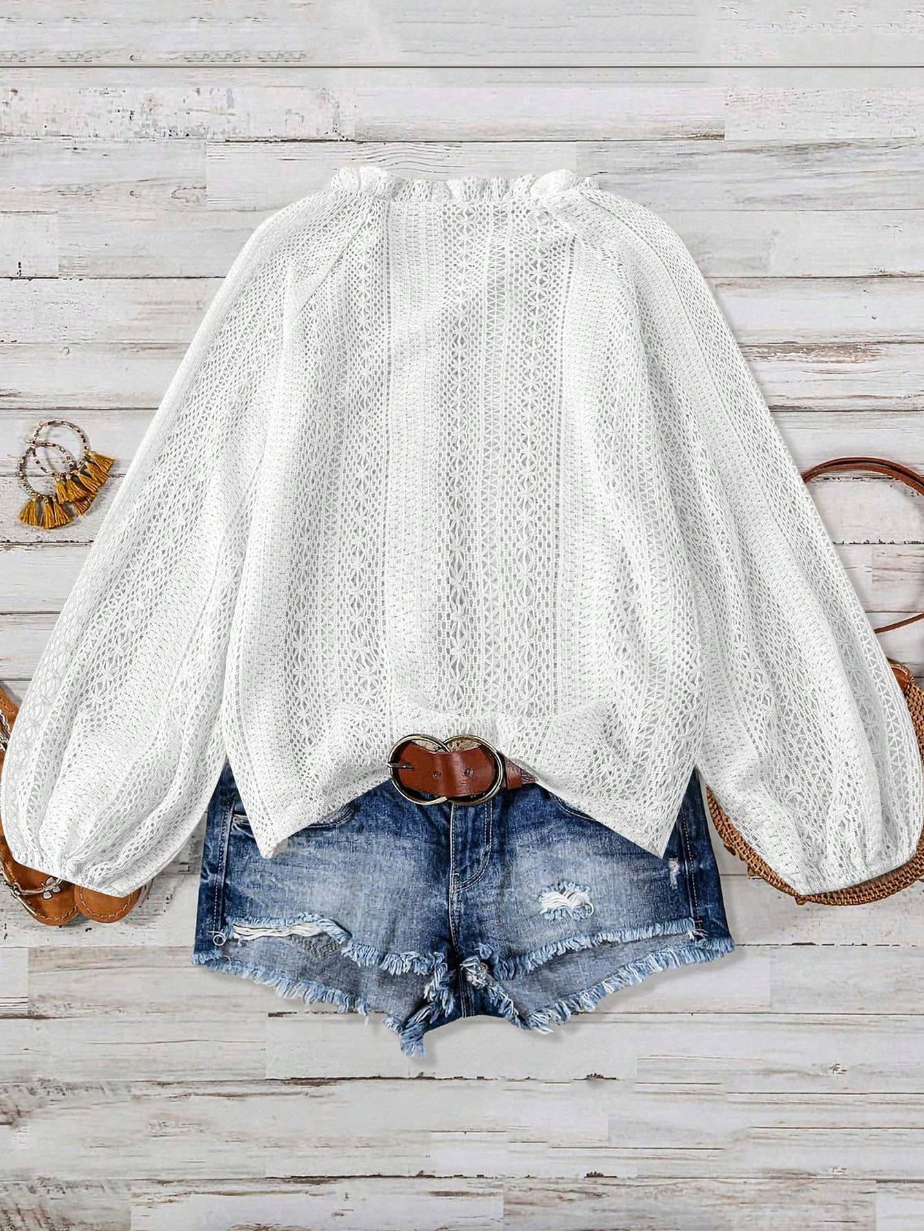 White lace blouse with balloon sleeves and denim shorts on a wooden surface