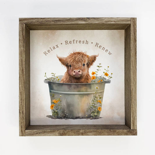 Framed artwork with a Highland cow in a bathtub and 'Relax Refresh Renew' text.
