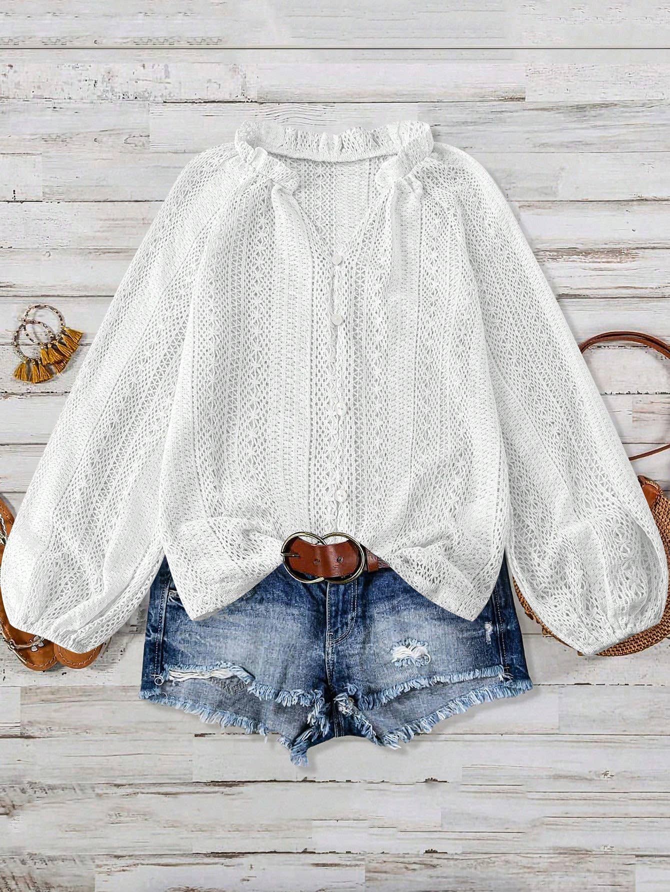 White lace blouse with puffed sleeves and denim shorts on a wooden surface