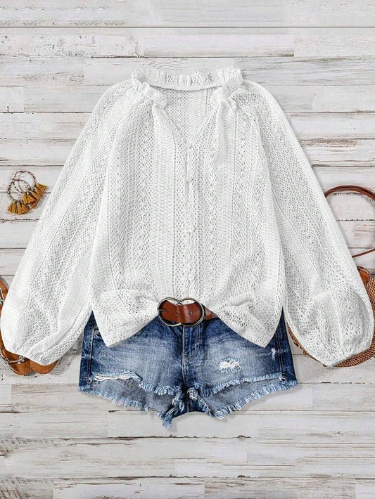 White lace blouse with puffed sleeves and denim shorts on a wooden surface