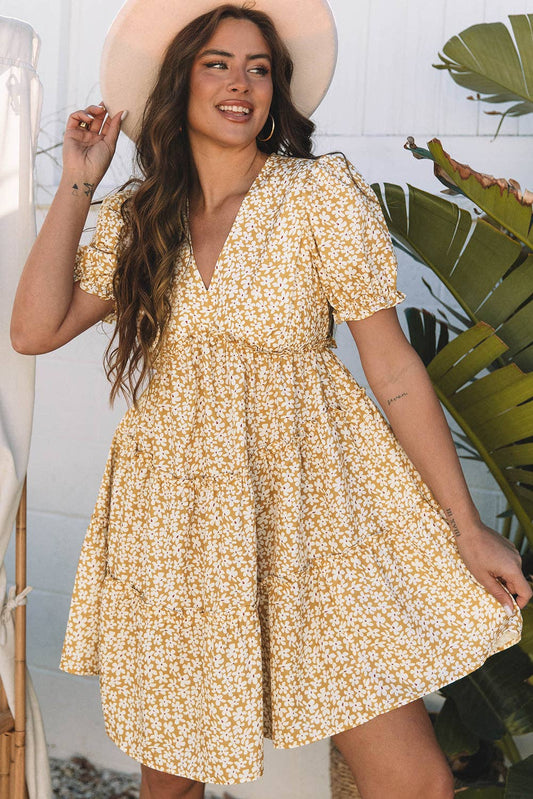 Woman wearing a yellow floral dress with a plant in the background