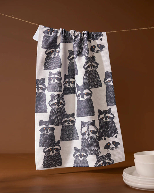 Geometry Tea Towel Banditbunch Towel with raccoon pattern hanging on a line against a brown background