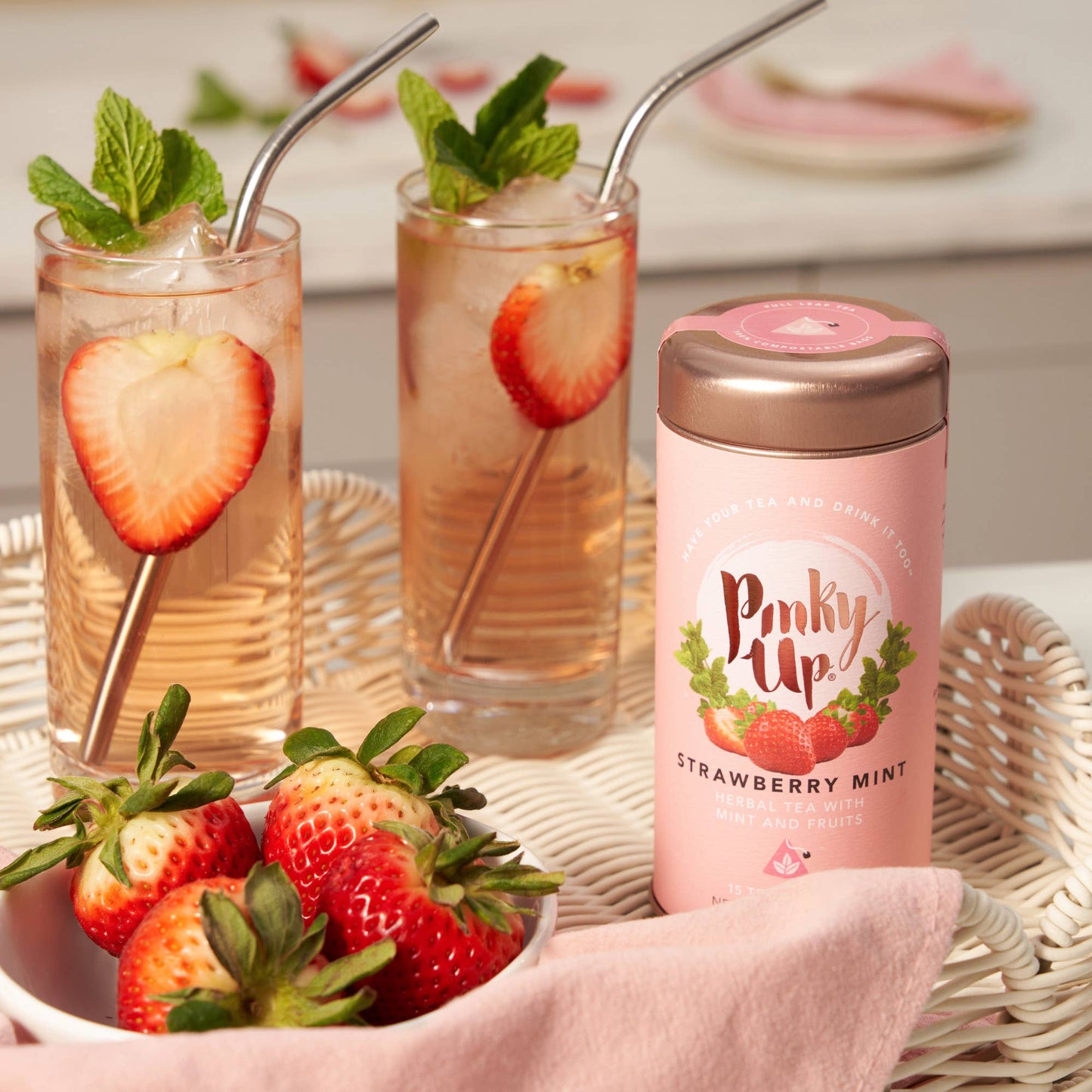Two glasses of strawberry lemonade with mint leaves and a pink 'Pinkie Up' strawberry mint drink container.