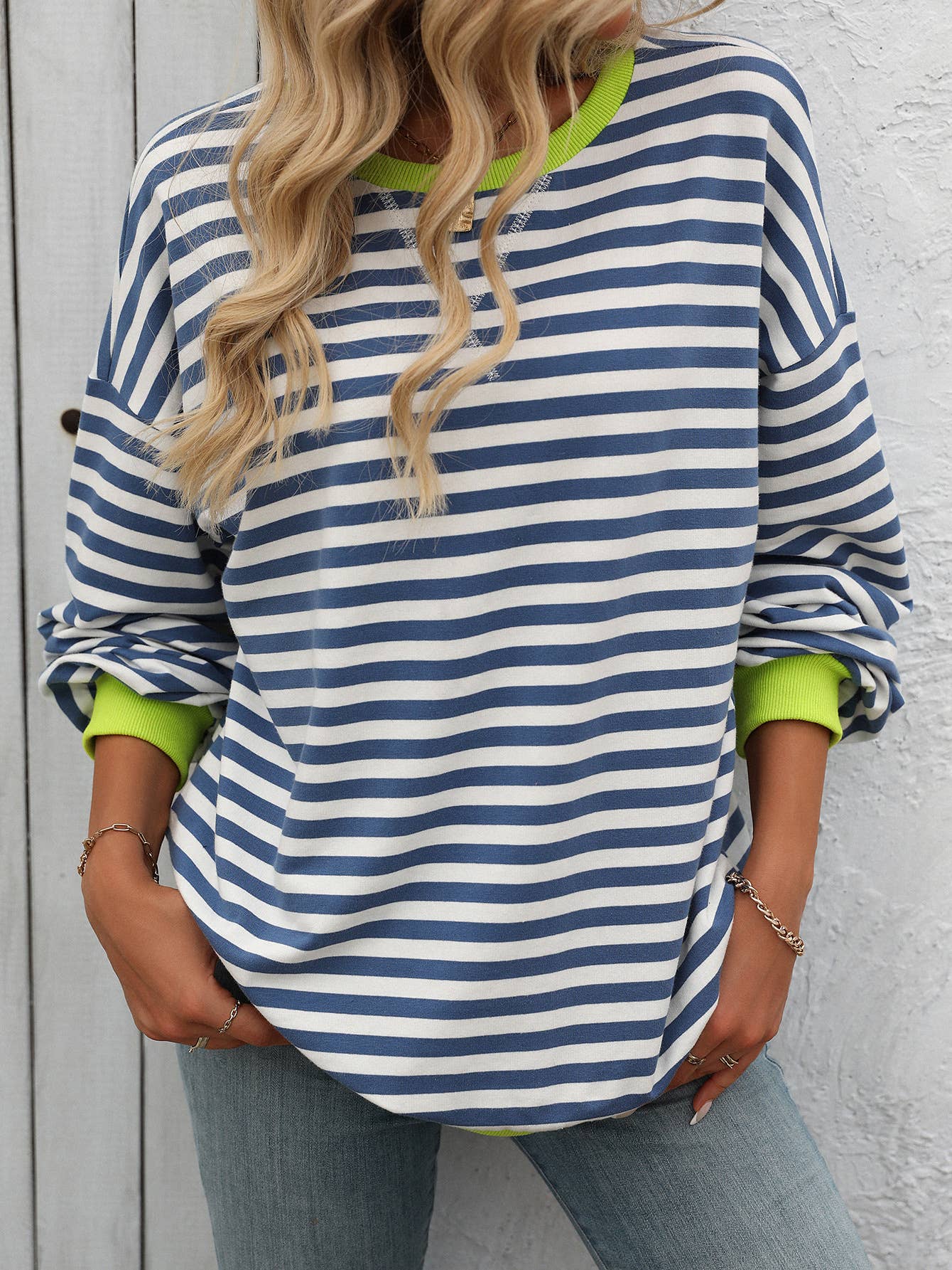 Person wearing a blue and white striped shirt with green cuffs and collar against a gray background