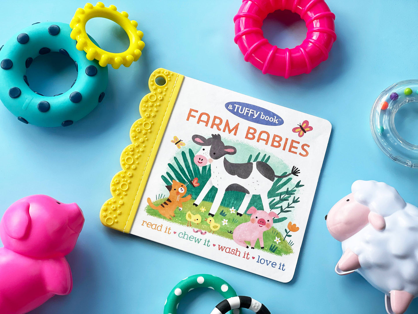 Children's book titled 'Farm Babies' surrounded by colorful toys on a blue background