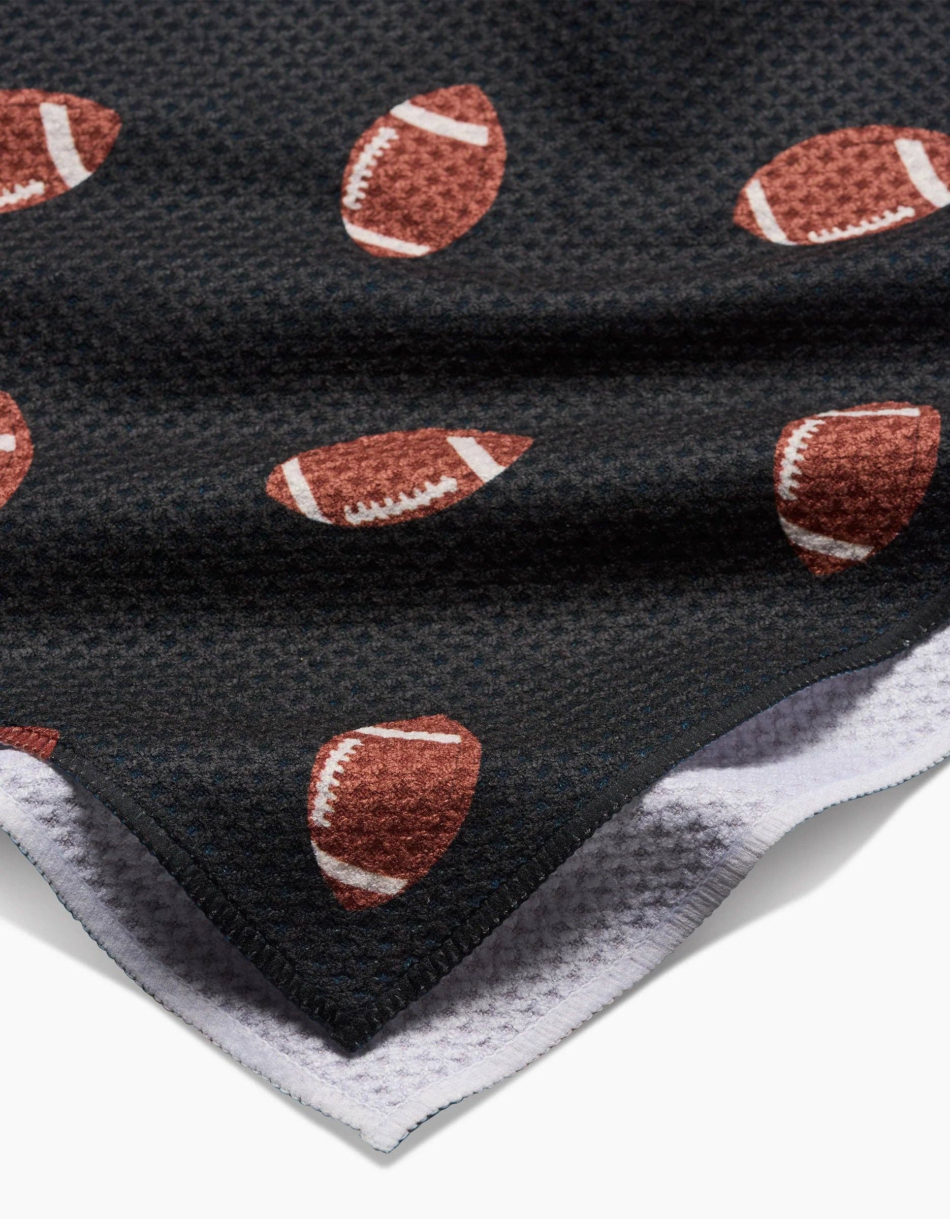Black Geometry brand kitchen tea towel with brown football pattern on a white background