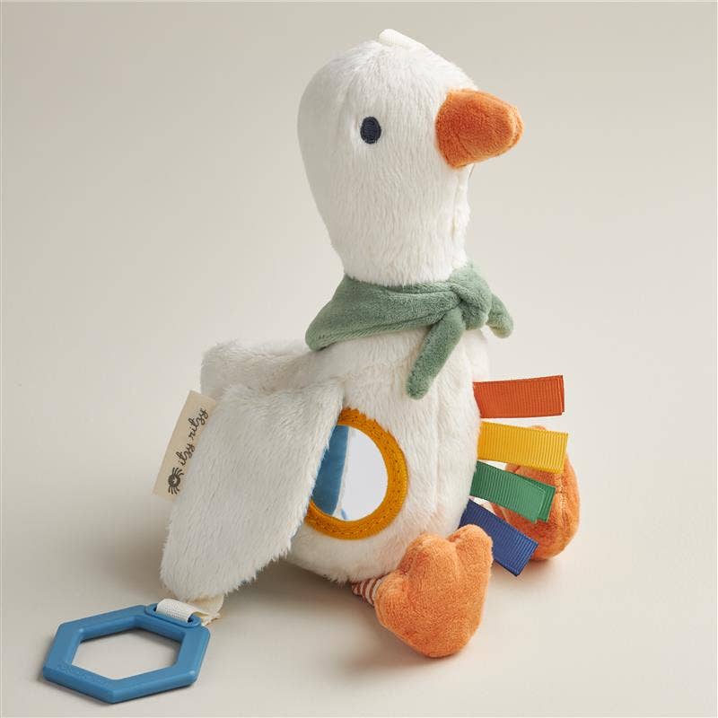 Plush toy goose with colorful patches and a blue tag on a light background
