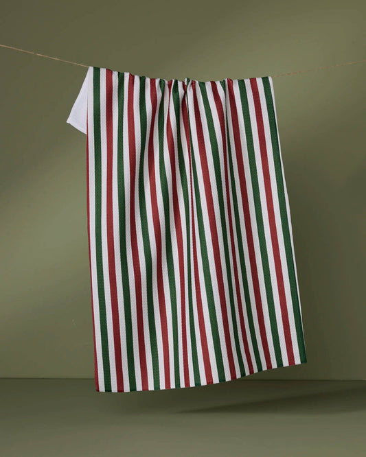 Geometry Tea Towel Ribbon Green Red  Striped towel with red, green, and white colors hanging on a line against a green background