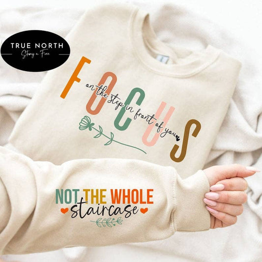 Sand cream sweatshirt with motivational text held by a hand, brand 'True North' visible