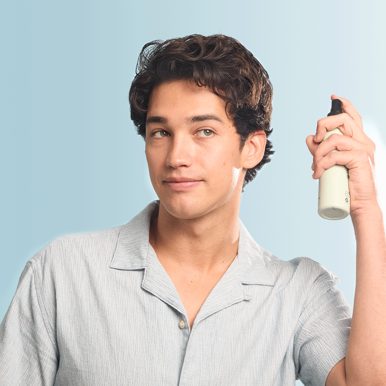 Man using texturizing sea salt spray on blue background