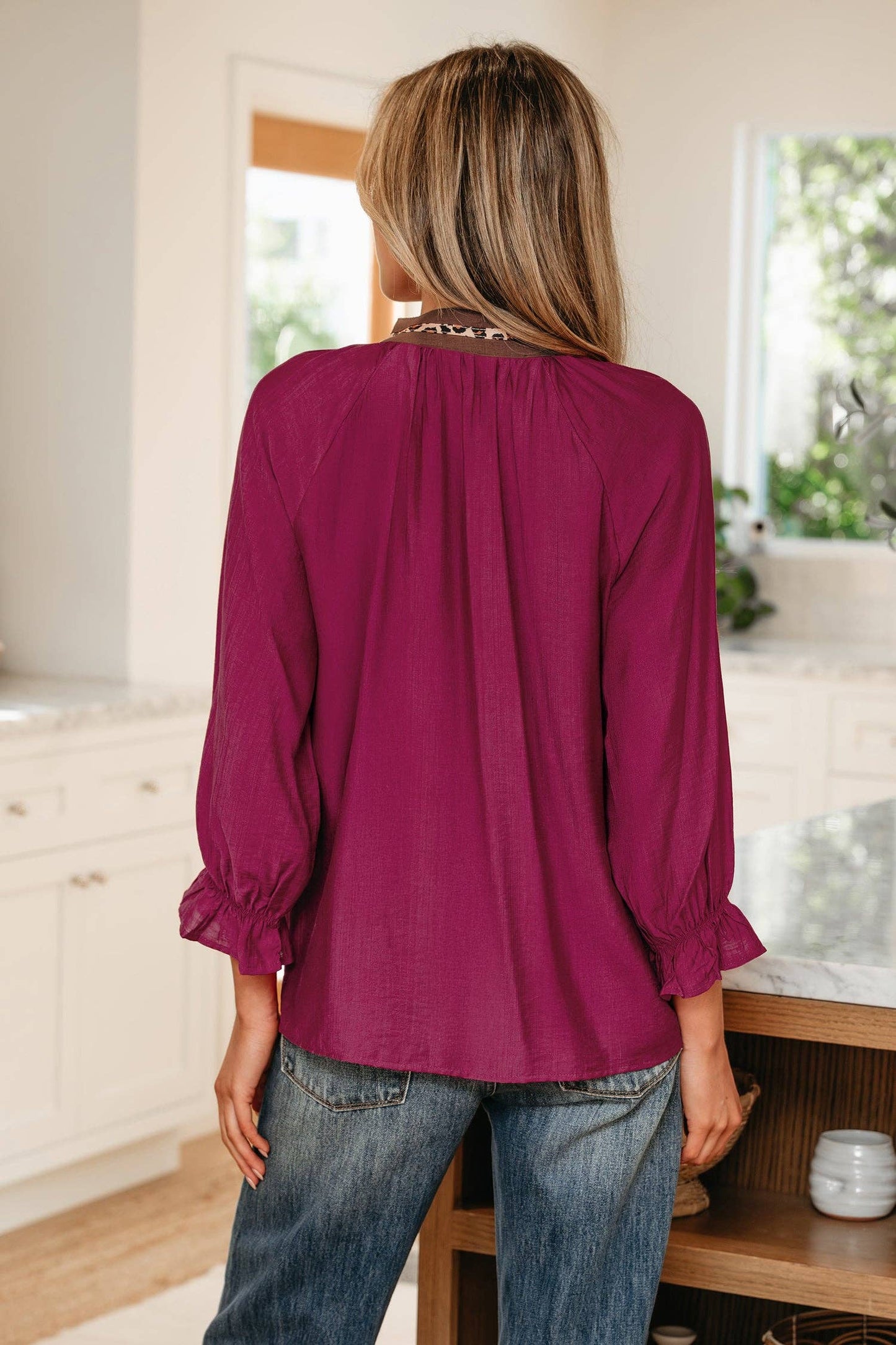 Person wearing a purple blouse and blue jeans in a kitchen setting