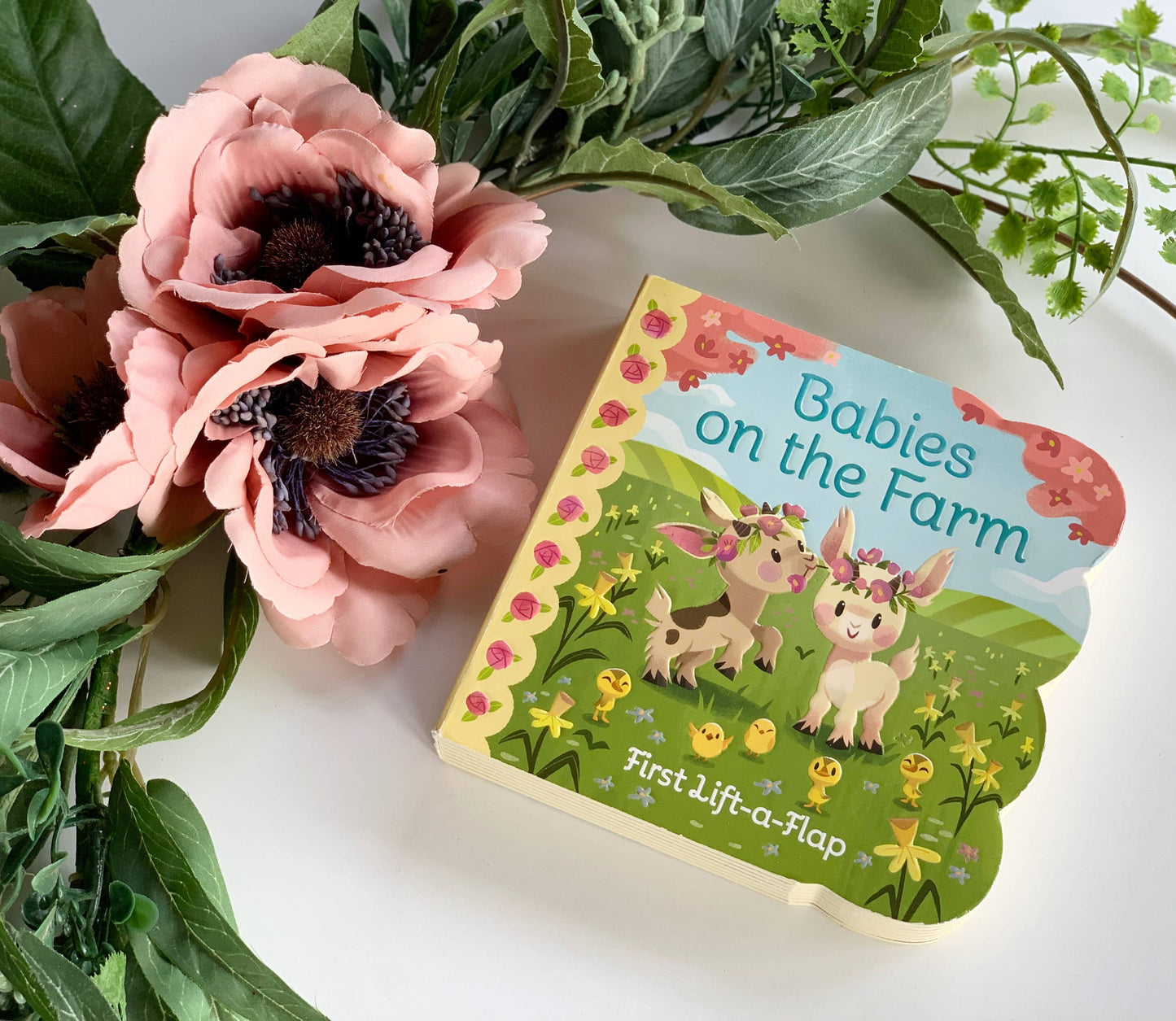 Children's book titled 'Babies on the Farm' with floral and greenery around