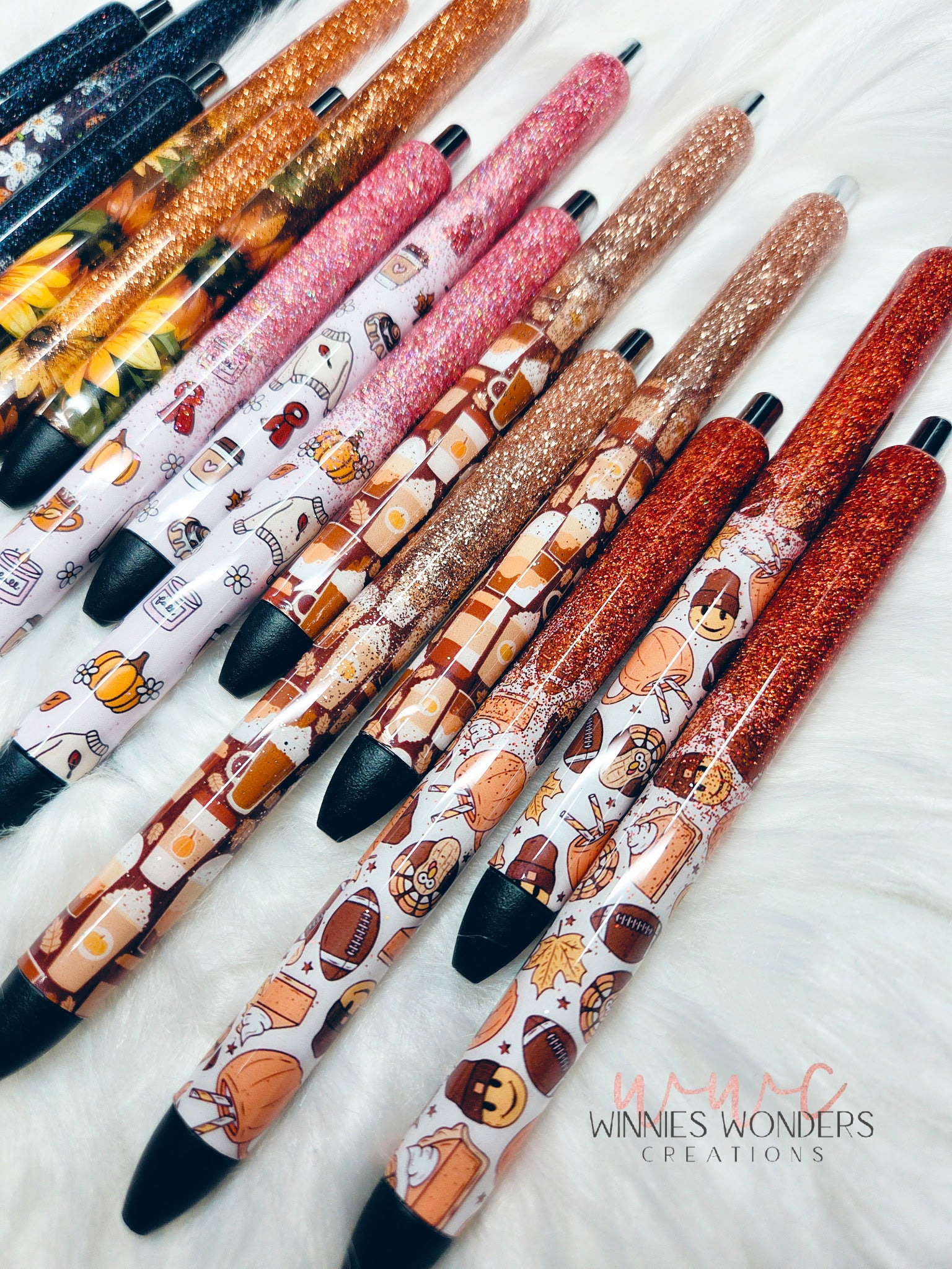 Decorative pens with various designs on a white surface, branded 'Winnie's Wonders Creations'.