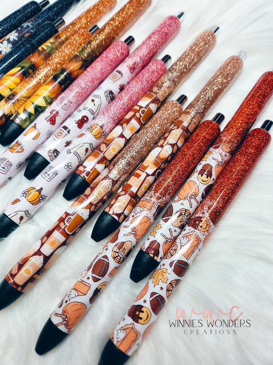 Decorative pens with various designs on a white surface, branded 'Winnie's Wonders Creations'.