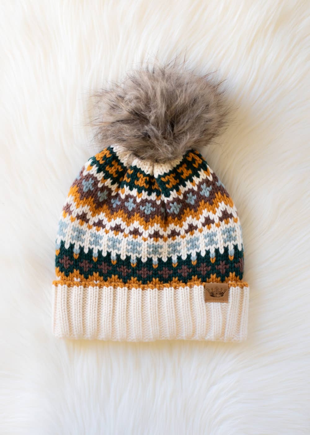 Knitted beanie with a patterned design and fur pom-pom on a white background