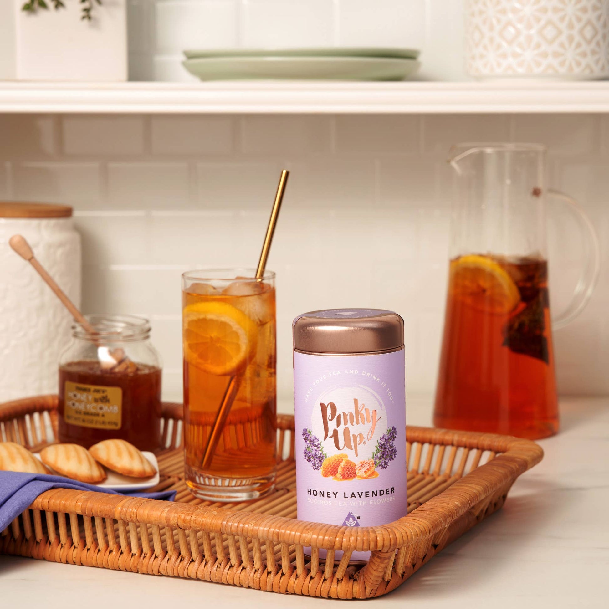Tea set with iced tea, cookies, and a canister labeled 'Pinky Up' on a kitchen counter.