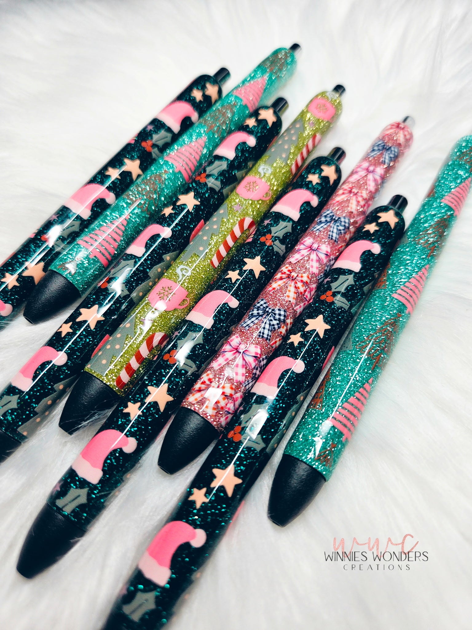 Decorative pens with glittery designs on a white surface