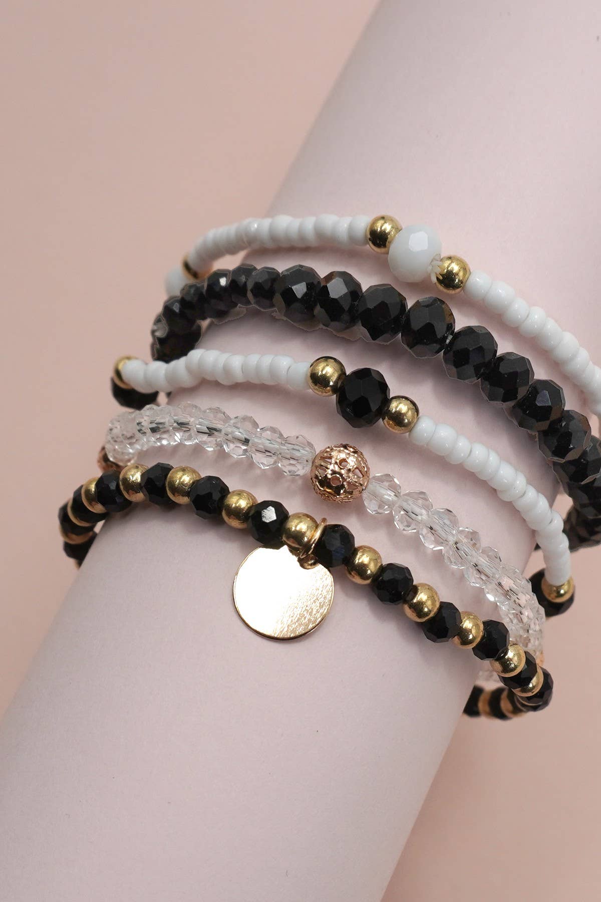 Set of beaded bracelets on a mannequin arm against a beige background