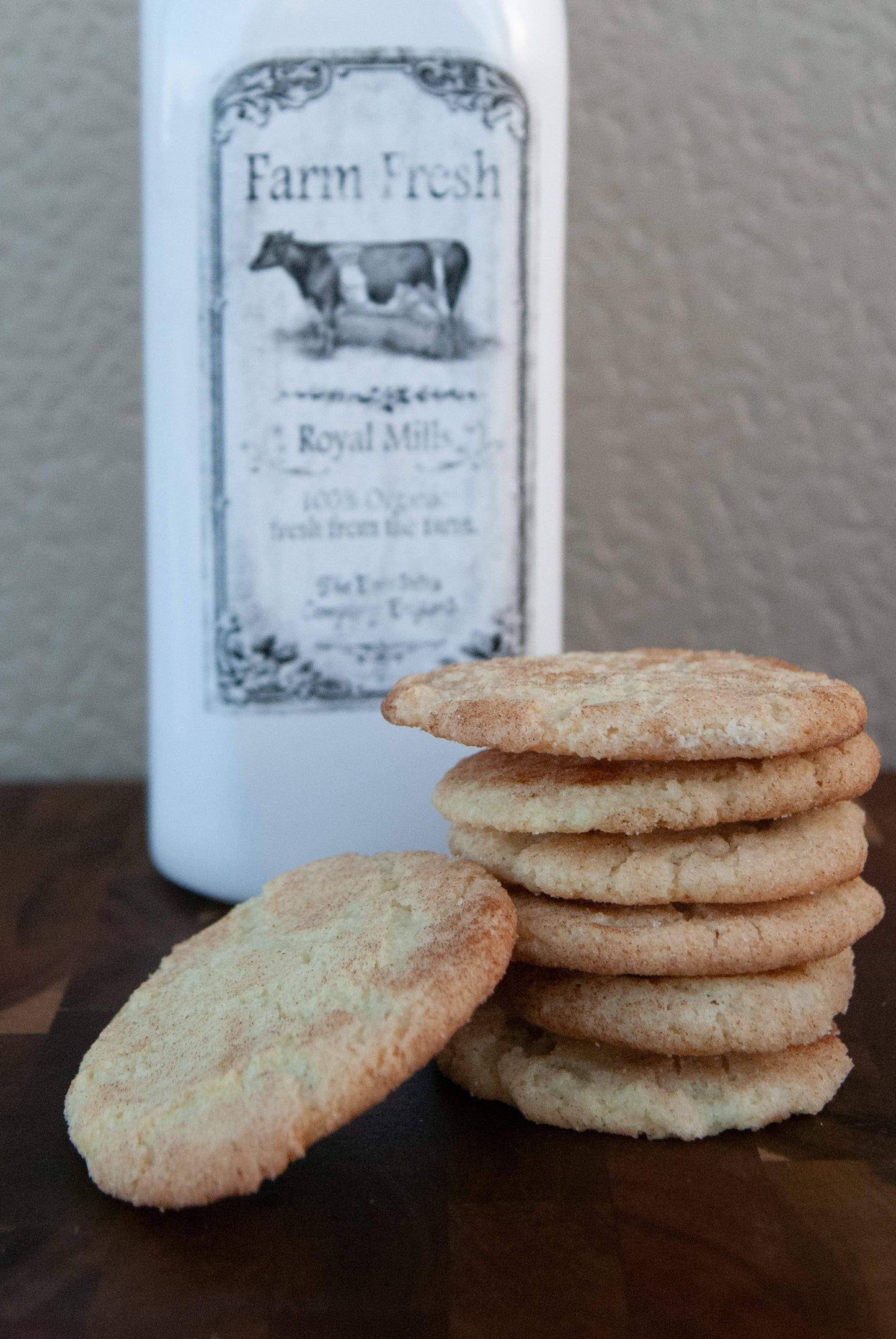 Stack of cookies with a bottle labeled 'Farm Fresh Royal Milk' on a wooden surface.