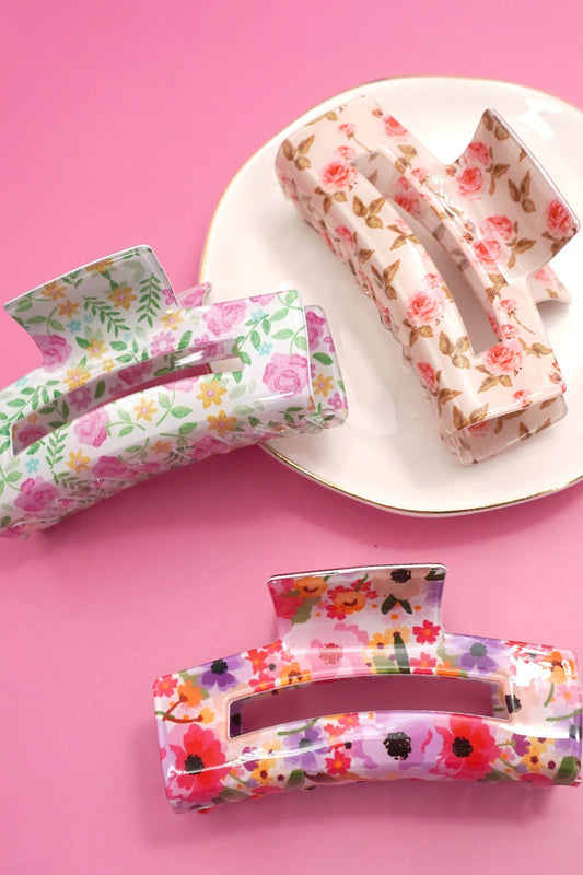 Floral-patterned hair clip on a white plate against a pink background