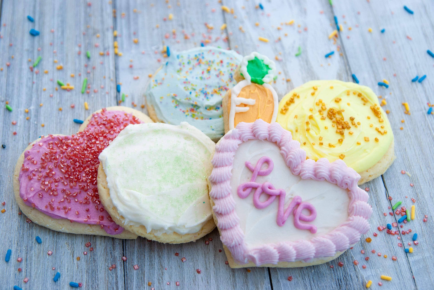 Decorative cookies with colorful icing and sprinkles on a wooden surface