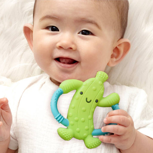 Baby holding a green teething toy with a smiley face