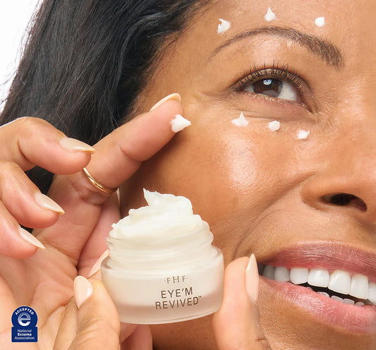 Woman applying cream to her eye area with a jar labeled 'Eye Revived' in the foreground.