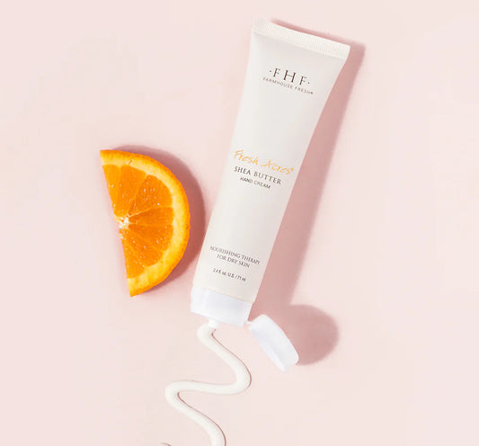 Tube of FHF fresh acres cream with an orange slice on a pink background