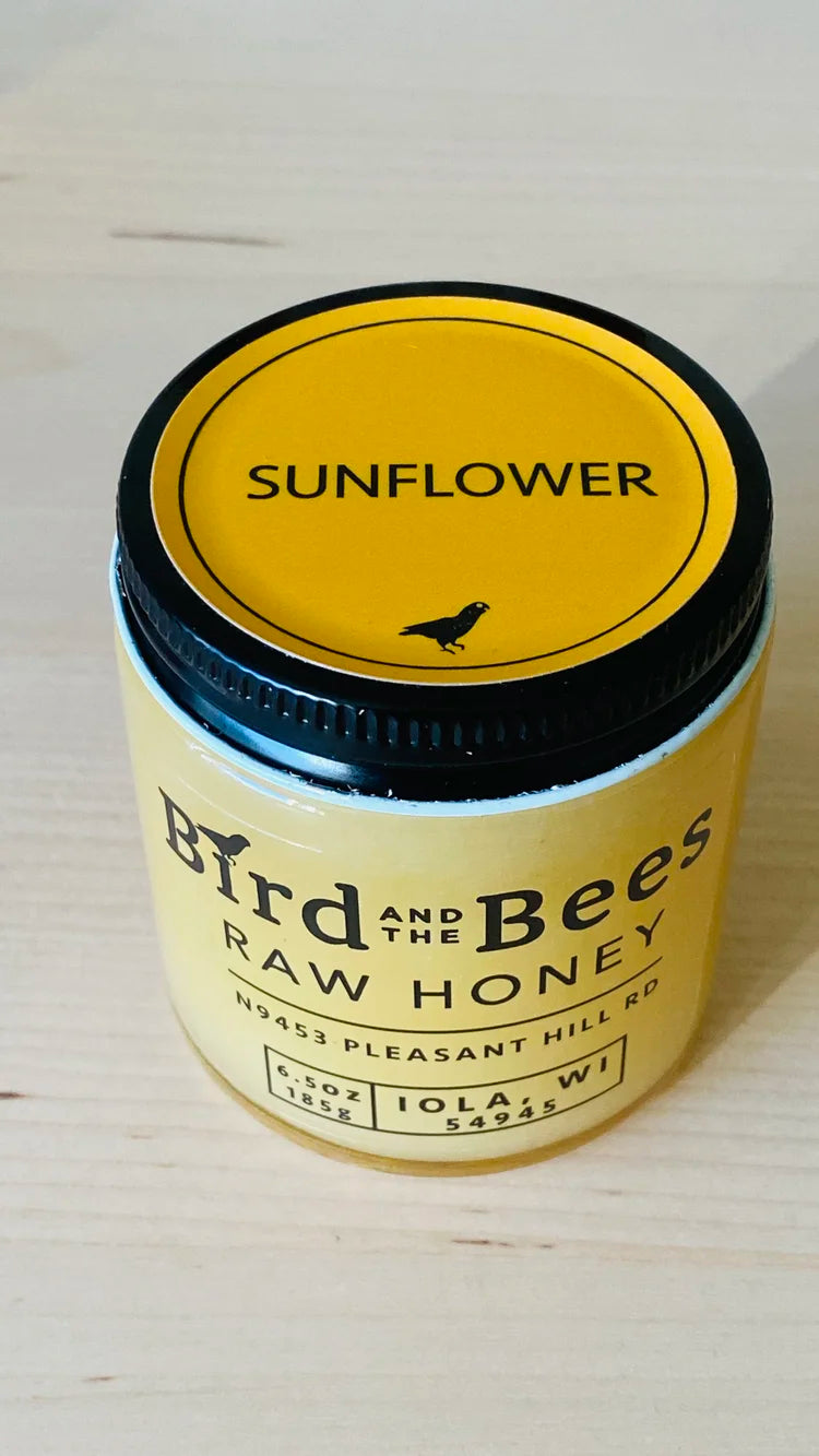 Jar of 'Bird and the Bees' raw honey with sunflower flavor on a light background