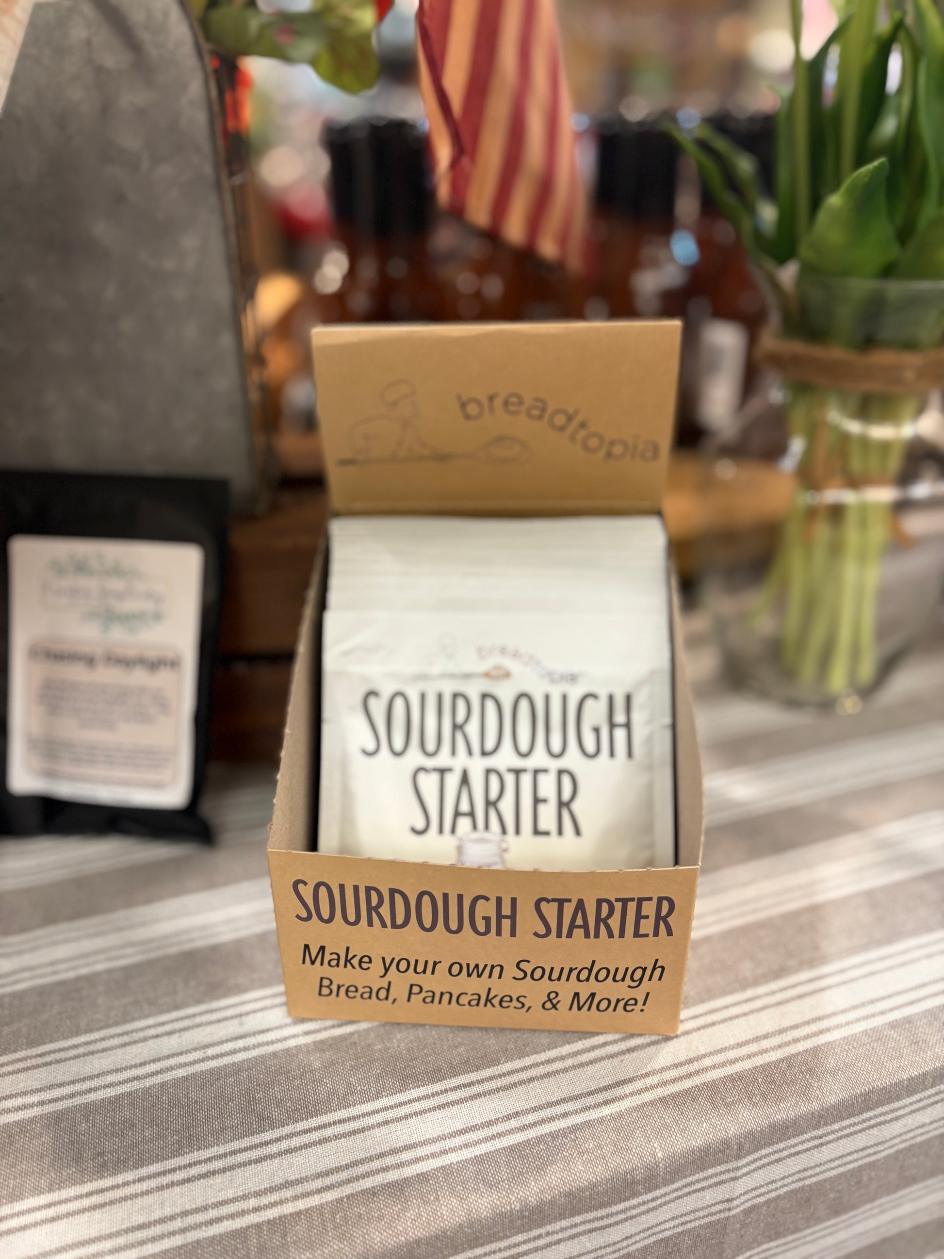 Sourdough Starter package on counter with striped tablecloth and flowers in the background