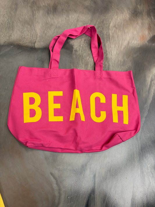 Pink tote bag with 'BEACH' in yellow on a gray surface