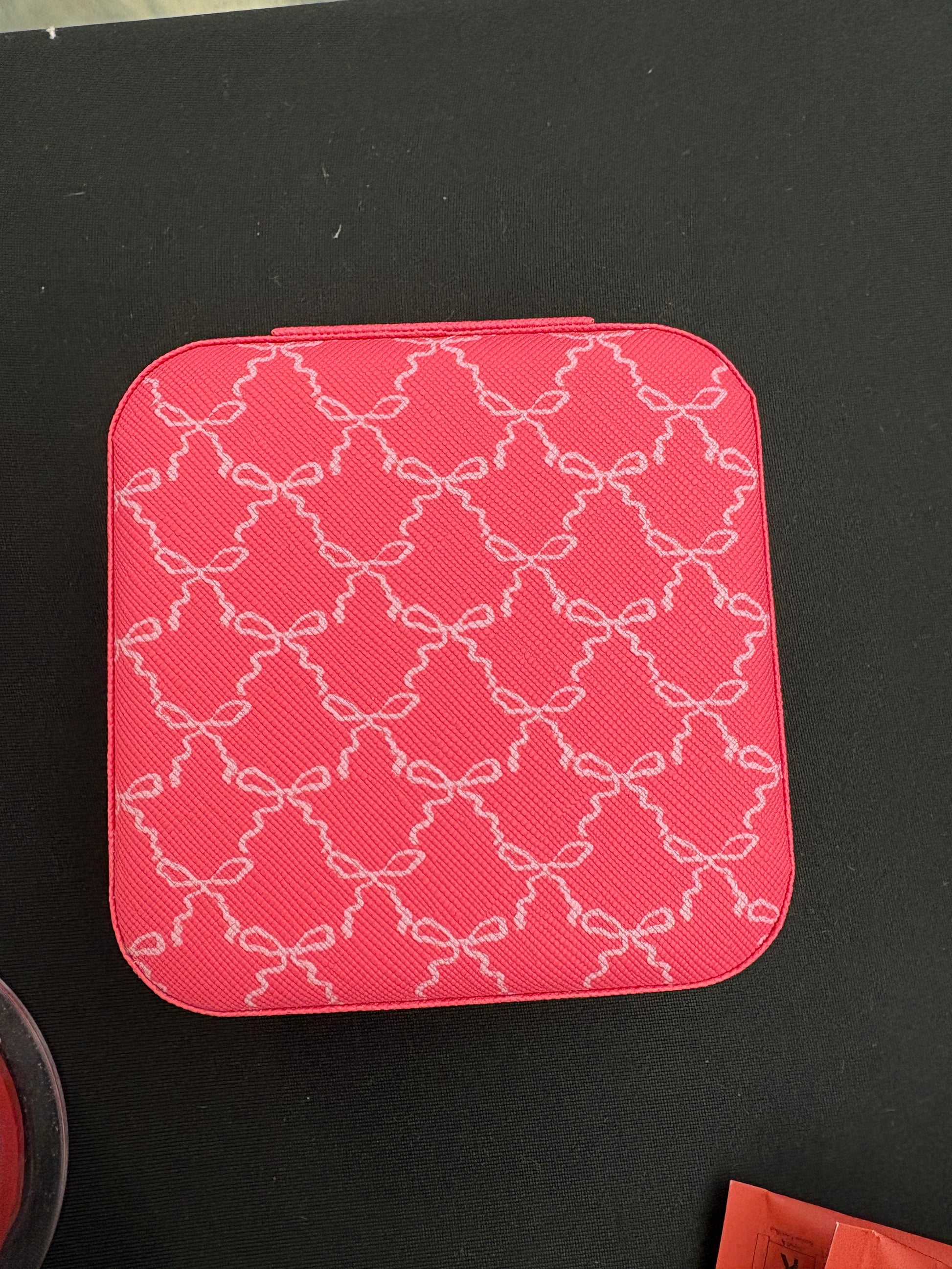 Pink textured square jewelry box on a black background